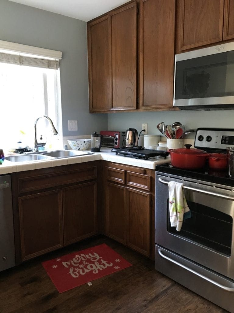 Before and After Kitchen Renovation with ideas and costs. See our farmhouse sink, herringbone backsplash with white subway tile and our DIY open shelving without changing our layout. Two-tone cabinets in woodgrain and blue. Including tips to get the most out of your budget. #kitcheremodel 