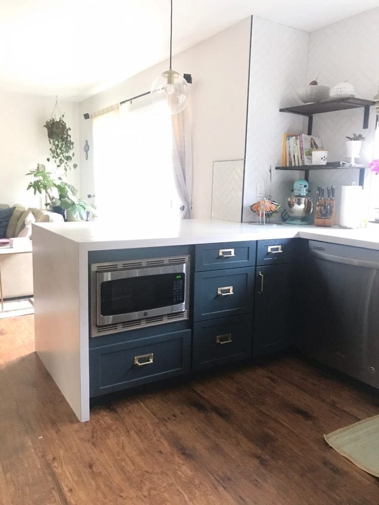 Before and After Kitchen Renovation with ideas and costs. See our farmhouse sink, herringbone backsplash with white subway tile and our DIY open shelving without changing our layout. Two-tone cabinets in woodgrain and blue. Including tips to get the most out of your budget. #kitcheremodel 
